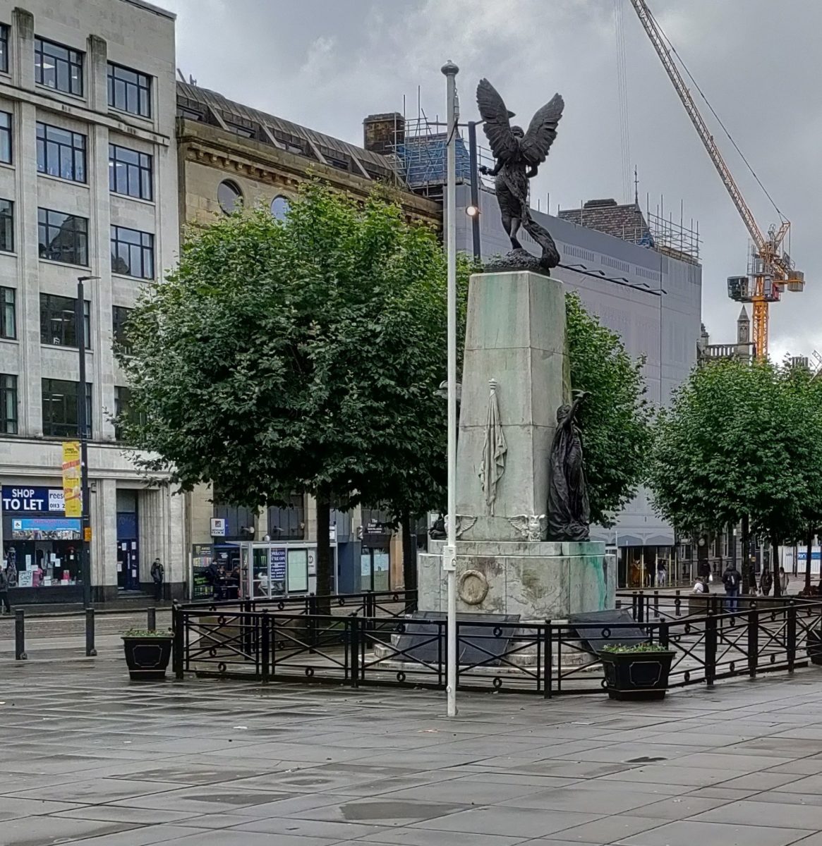 A cenotaph in Leeds city centre surrounded by puddles and grey skies.
