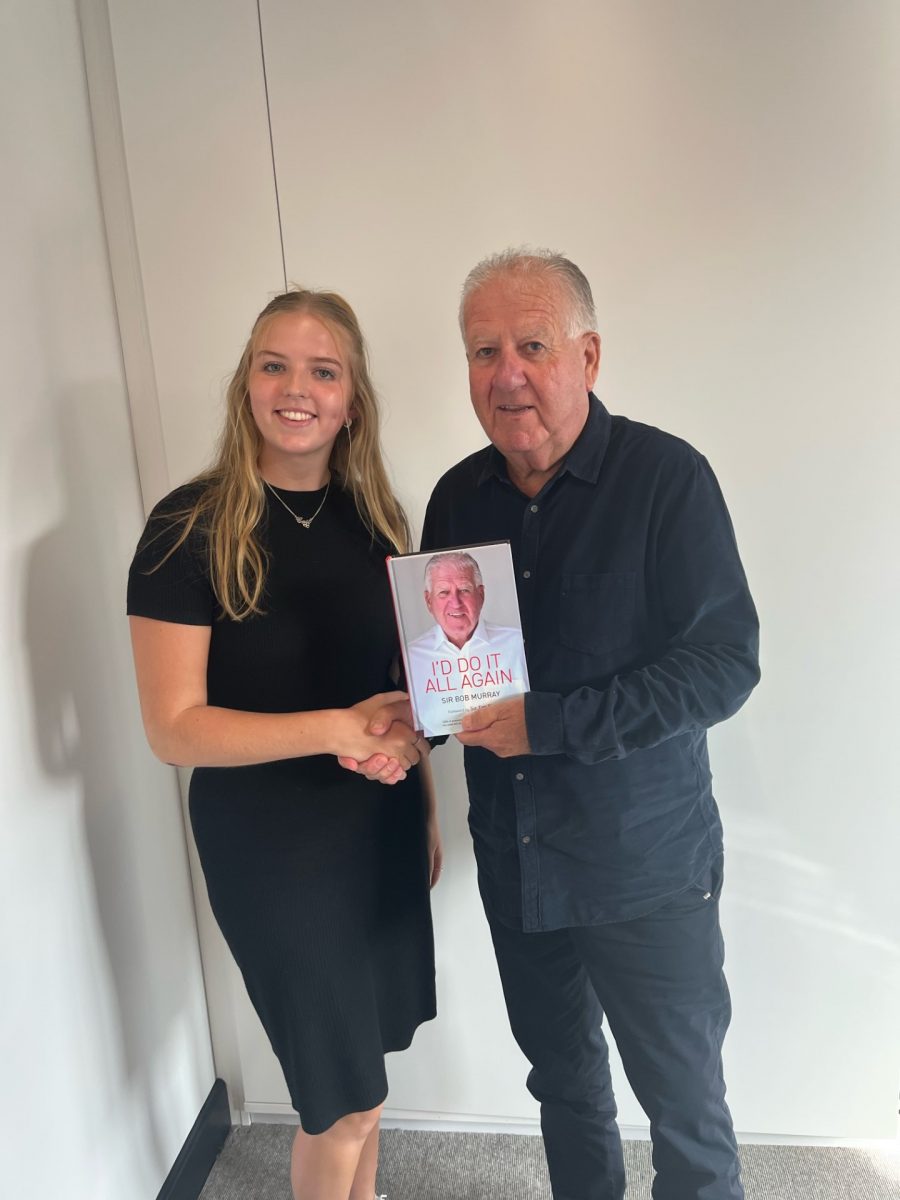 Sir Bob Murray stood holding his autobiography "I'd Do It All Again"