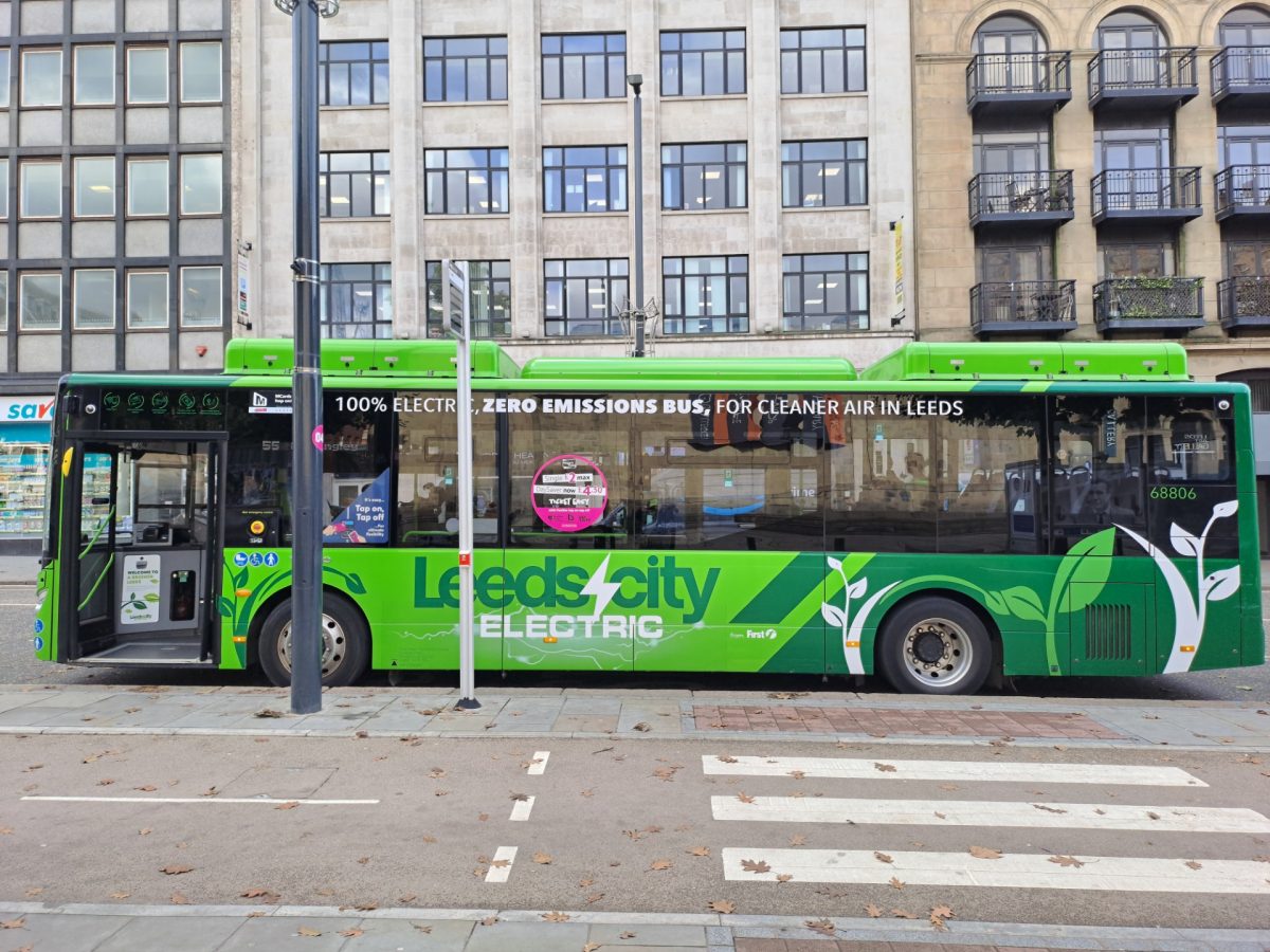 A green Leeds City bus parked next to a bike lane