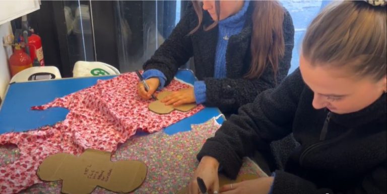 two girls drawing arounnd stensils on fabric to make reusable sanitary pads
