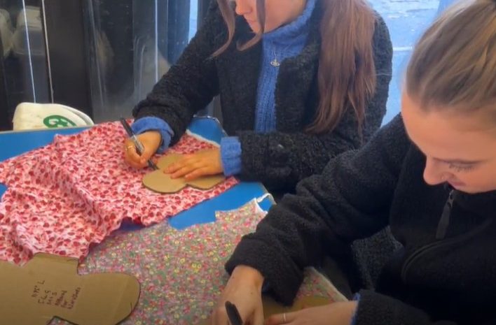 two girls drawing arounnd stensils on fabric to make reusable sanitary pads