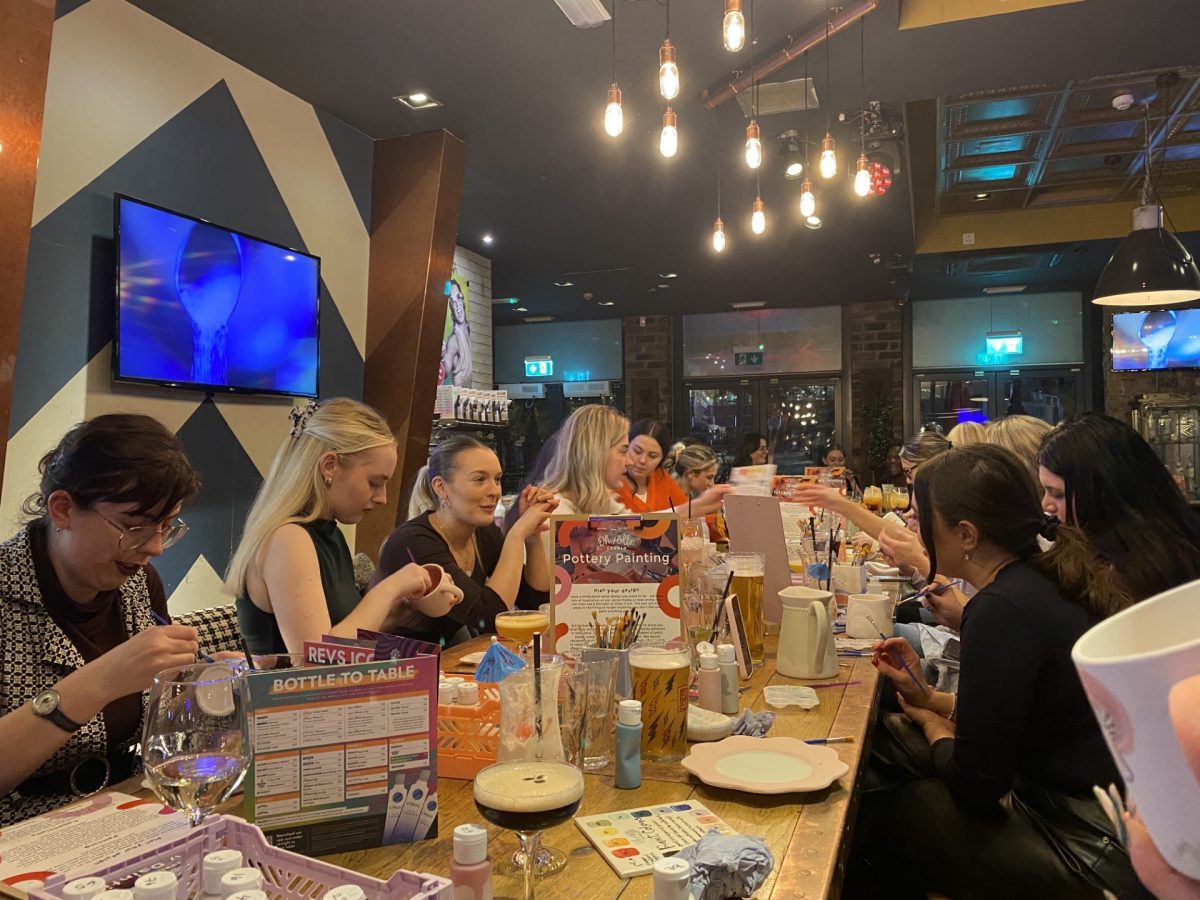 group of women sat at a table painting pottery