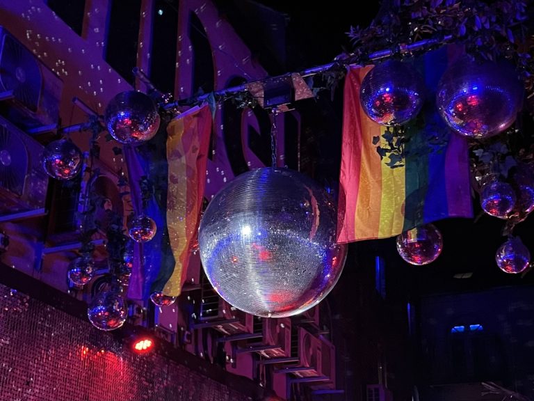 One big mirror ball in between two pride flags