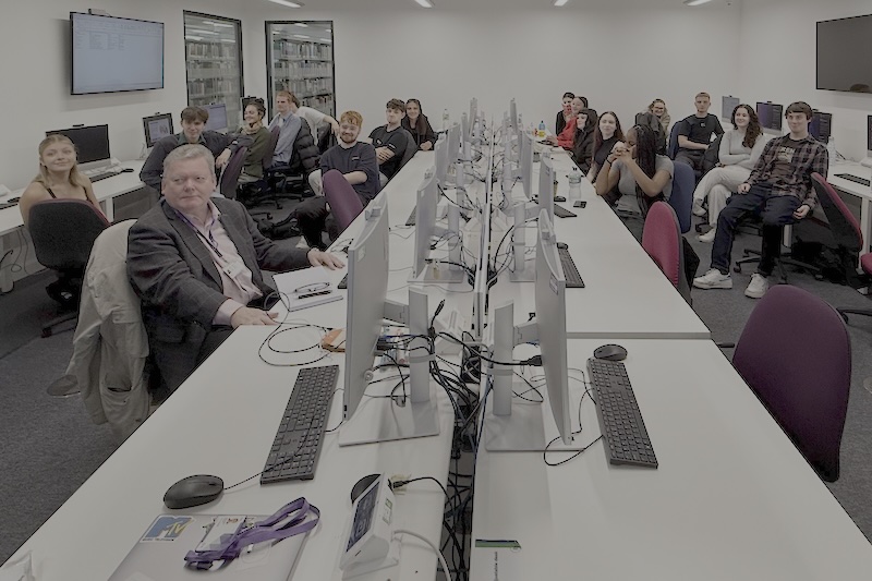 A group of people in a computer room looking at the camera