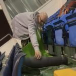 A man who is stood in the stand of Headlingley stadium rolling out a sleeping mat as he sets up his bed for the night