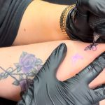 This is a close up image of a tattoo artist inking somebody's arm. They appear to be doing a butterfly design