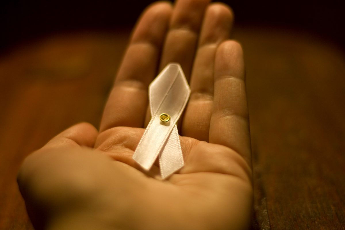 This image depicts a small white ribbon in the palm of a hand