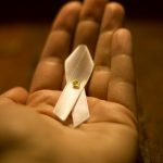 This image depicts a small white ribbon in the palm of a hand