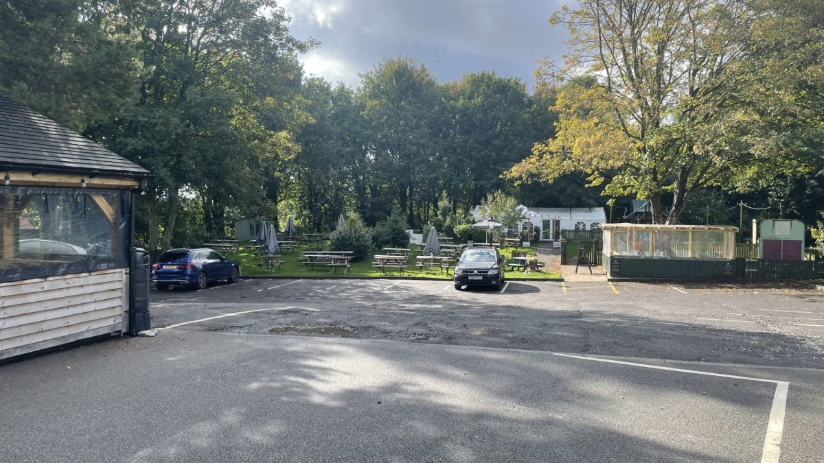 Picture of the pub garden with greenery visible as well as benches.