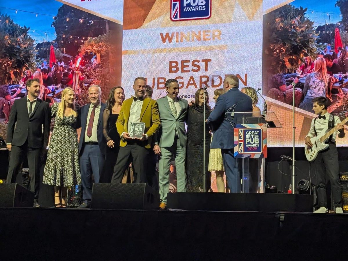 Photo of the Myrtle Tavern owner collecting the award of best pub garden with a gleeful smile.