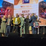 Photo of the Myrtle Tavern owner collecting the award of best pub garden with a gleeful smile.