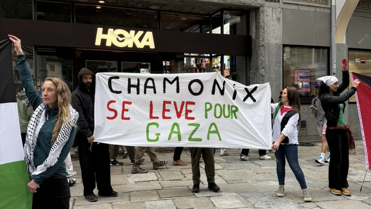 people holding protest banner in french "Chamonix se leve pour gaza" written in black, green and red on white banner