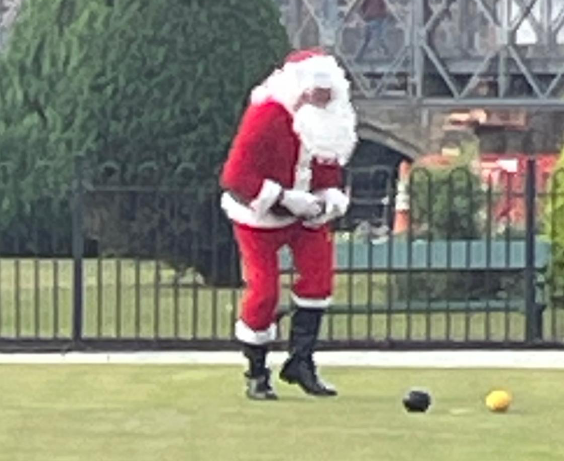 Someone dressed as Santa collecting bowling balls on a field.