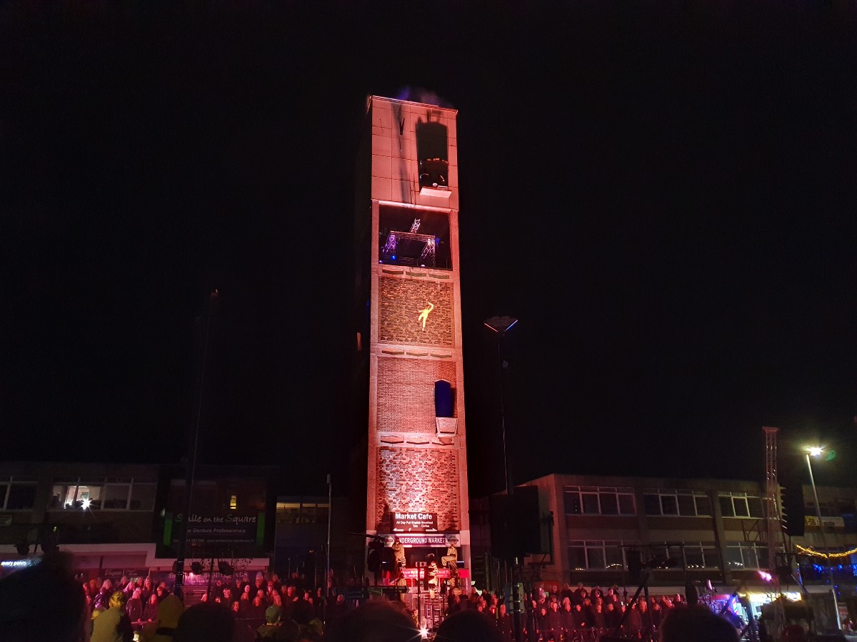 The image shows a performer scaling the clocktower in Shipley