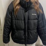 Black puffer jacket with white text on chest reading “lets frus...”.