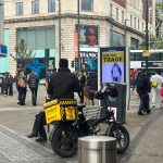Close up of delivery driver on e-bike with yellow bag on the back