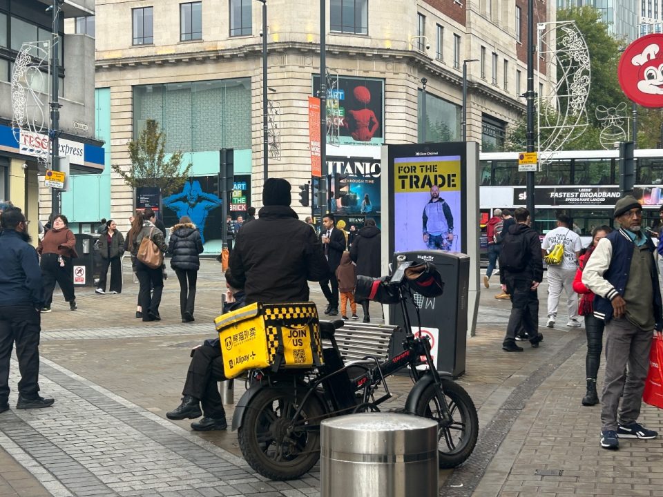 Close up of delivery driver on e-bike with yellow bag on the back
