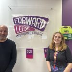 A man and a woman stood in front the 'Forward Leeds' sign.