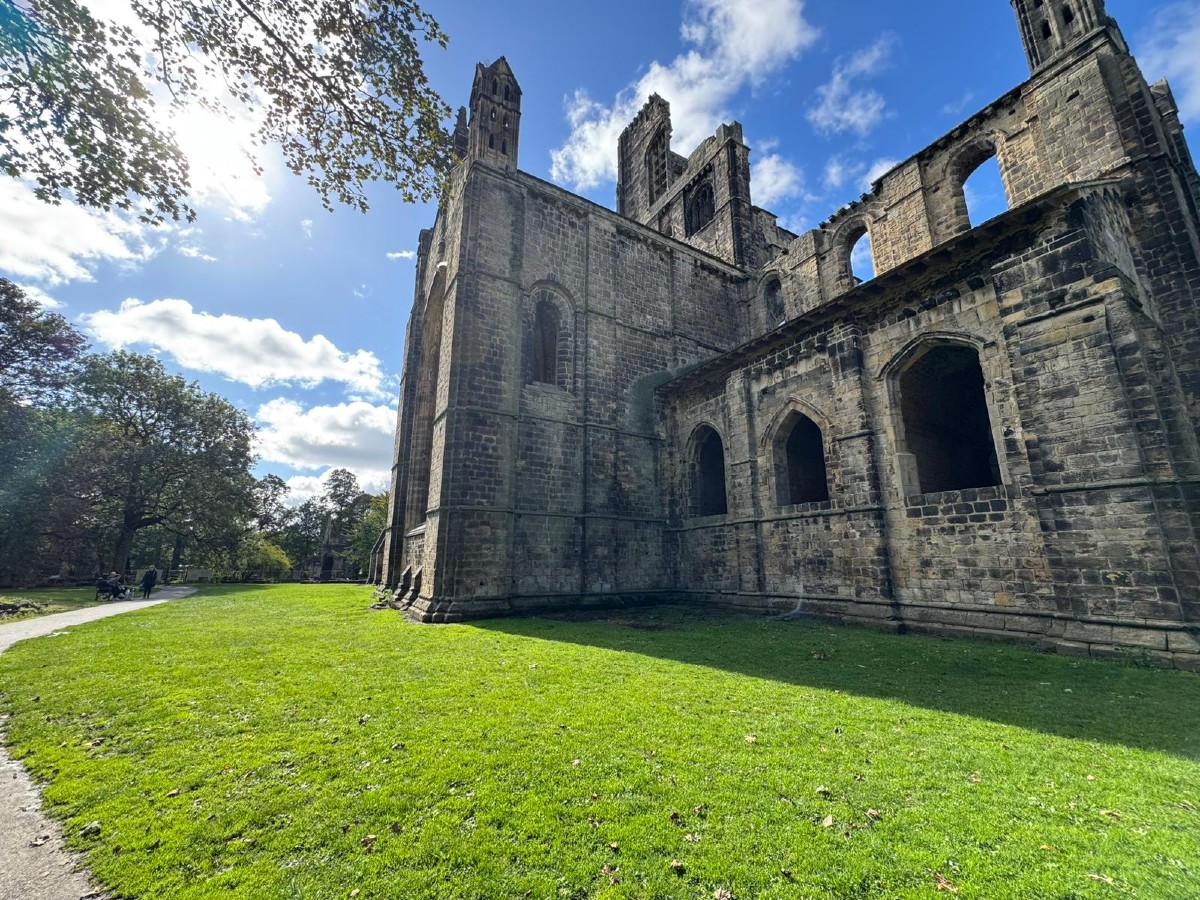 The image shows Kirkstall Abbey in Kirkstall on a sunny day