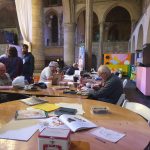 The image shows people round a table drawing in a church