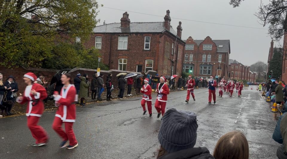Runners dressed up as Santa are caught in action running down a rainy street.