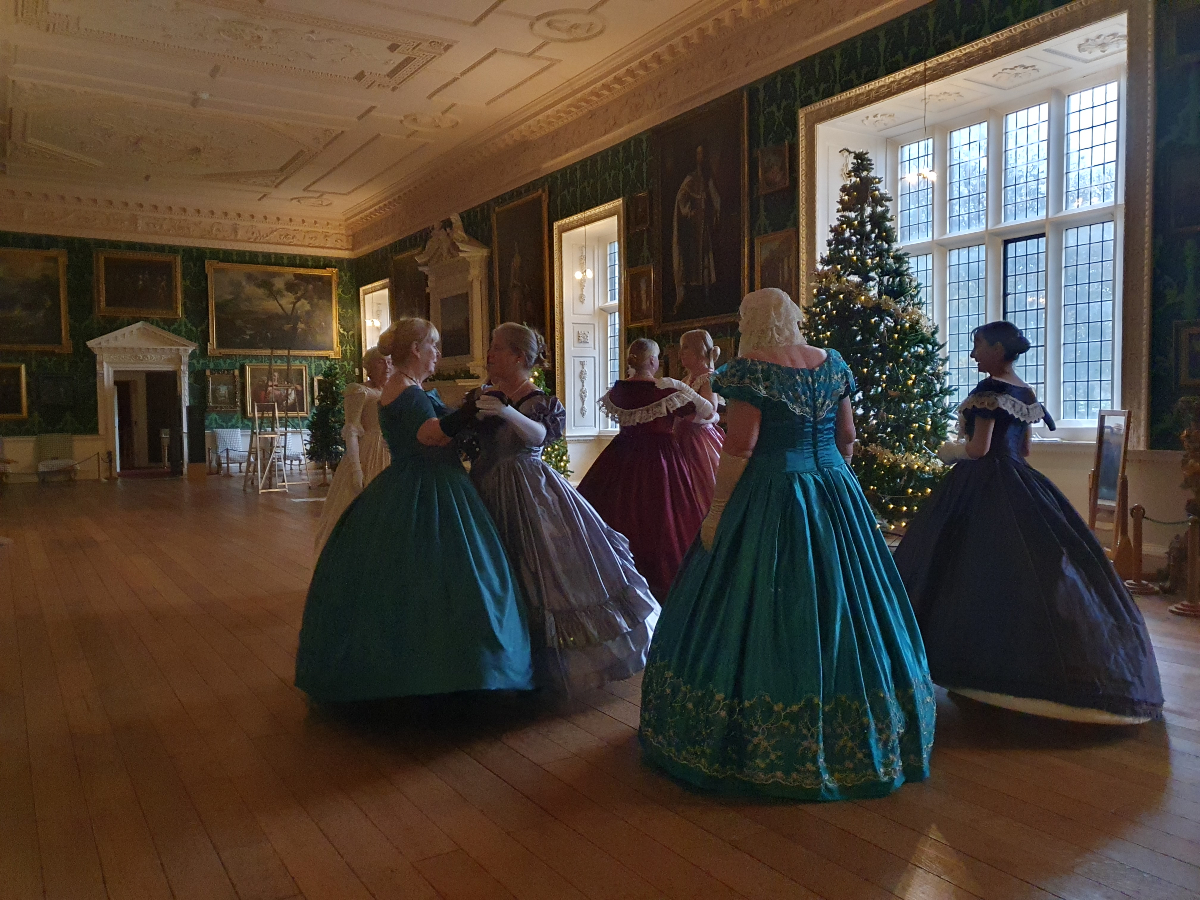 The image shows dancers in front of a christmas tree