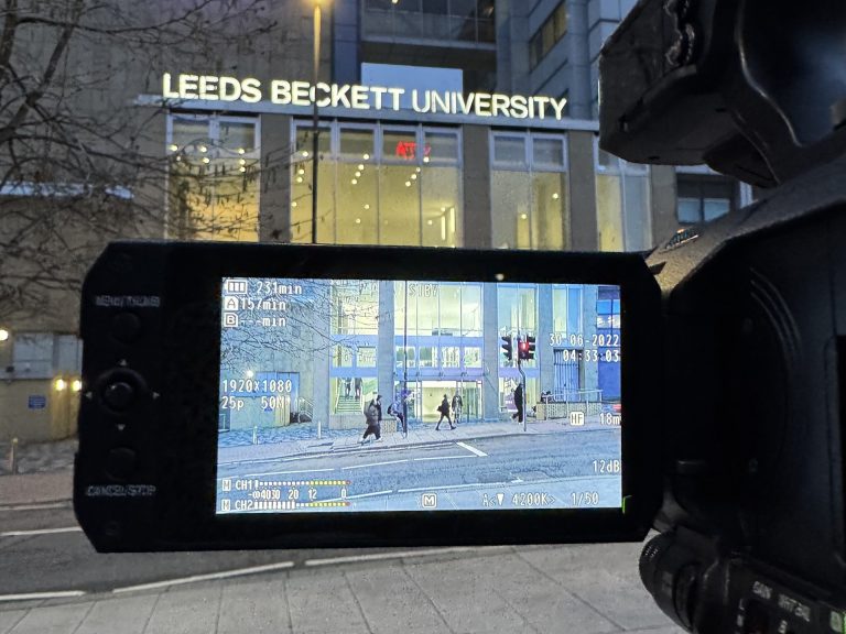 Leeds Beckett University florescent sign, with a camera display in the foreground.