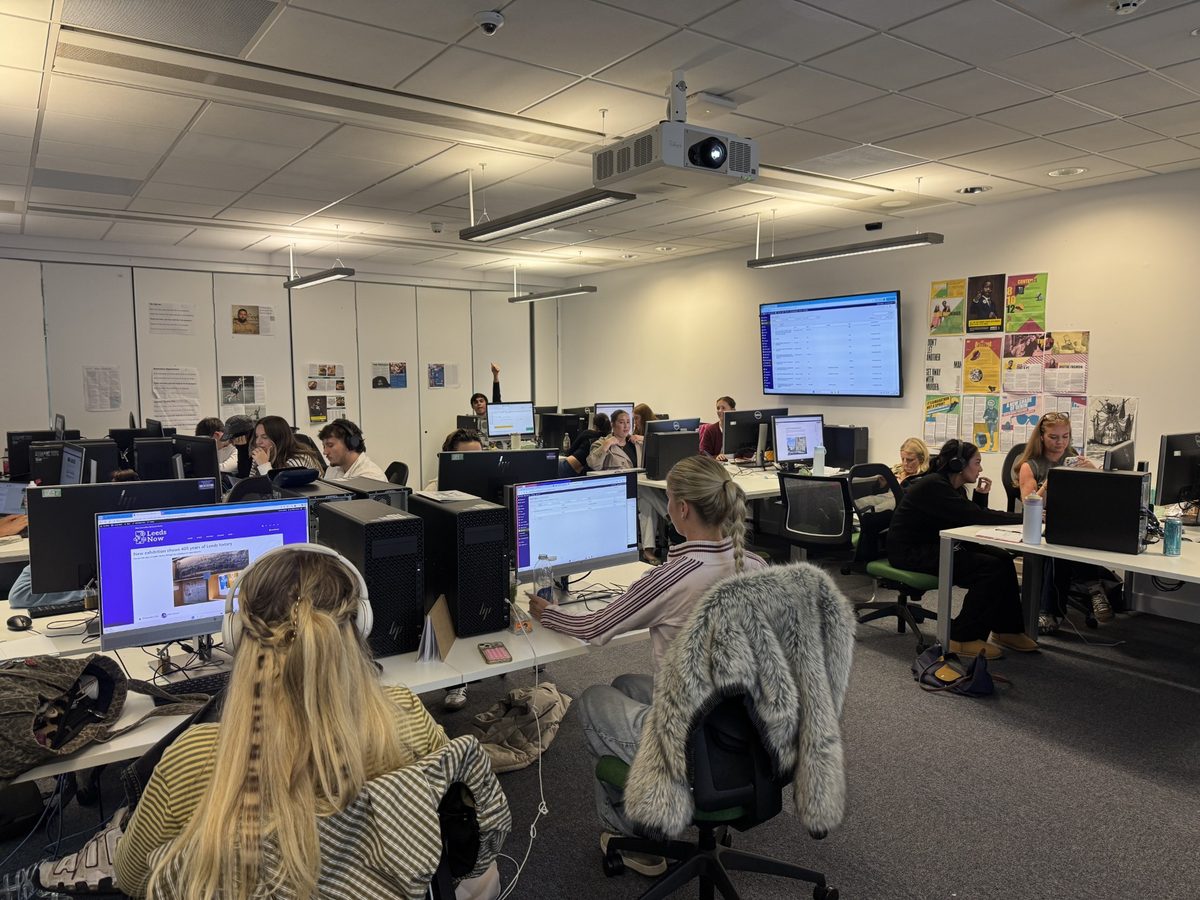 A classroom full of students working sat down at computers.