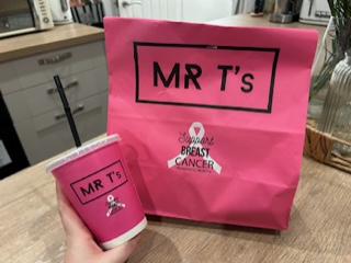 Image features hand holding a pink Mr Ts cup in front of a pink takeaway bag.