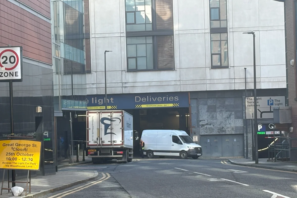 A lorry and a white van parked outside a city shopping centre designated delivery entrance. 